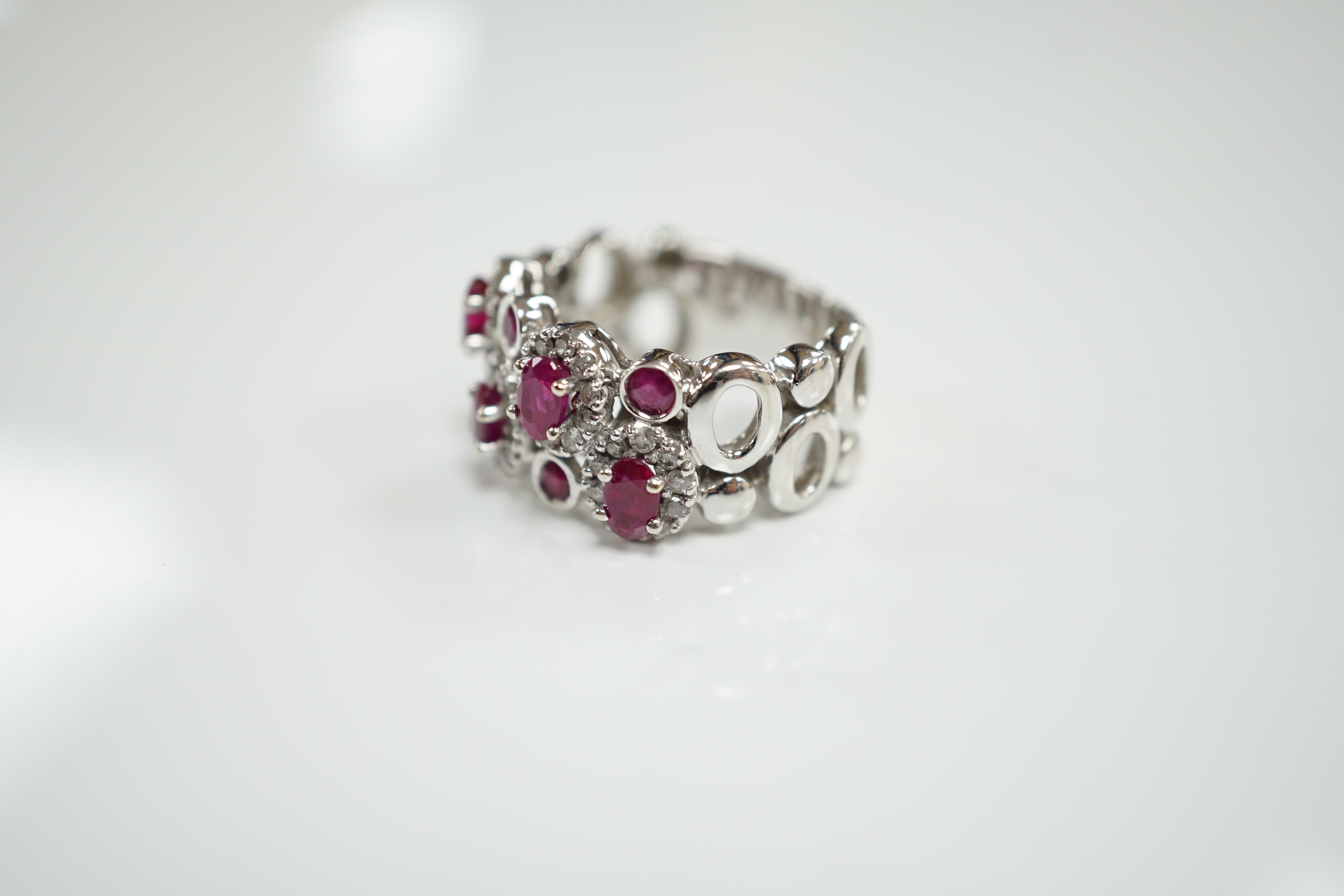 A modern 14ct white gold, ruby and diamond set multi cluster half hoop dress ring, size O, gross weight 8.1 grams.